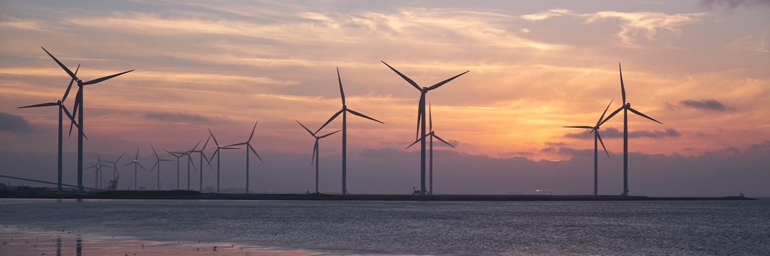 A number of wind turbines in the distance at sunset